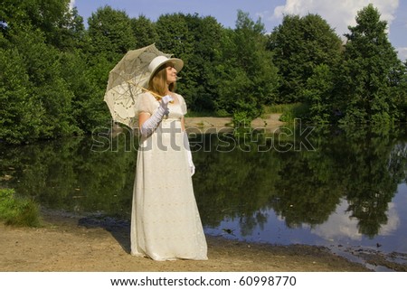 Young woman in white historical dress of nineteen century with white umbrella in white hat near lake in park, summer.
