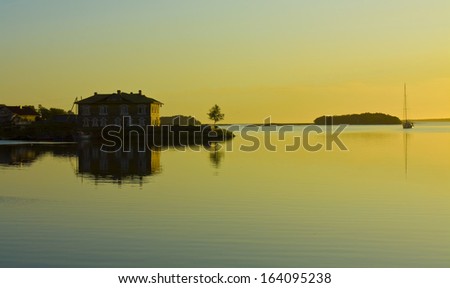 Landscape: sunset on sea, house and little tree on coast and little island on horizon, recorded on Big island of Solovki (Solovetskiy) archipelago on White sea, North of Russia.