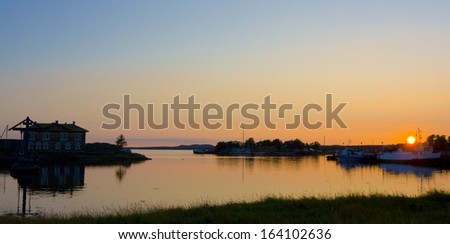 Landscape - sunset on sea, house and little boats on shore. Recorded on Solovki islands on White sea, Russia.