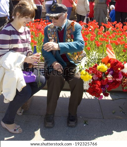 MOSCOW - MAY 9, 2014: Holiday Victory Day devoted to victory in Second World War, young girl presents flowers to war veteran on the street.