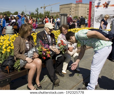 MOSCOW - MAY 9, 2014: Holiday Victory Day devoted to victory in Second World War, young man makes a bow to war veteran on the street.