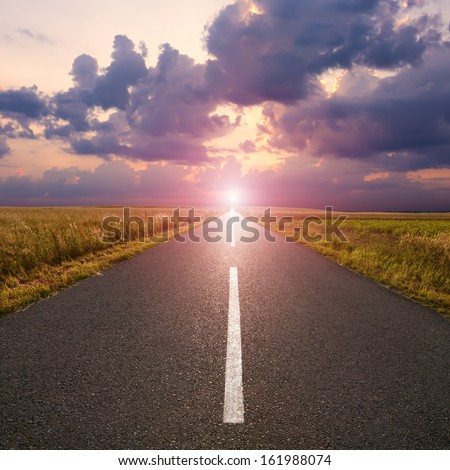 Driving on an empty asphalt road to the rising sun