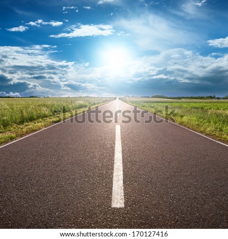 Driving on an empty road towards the sun