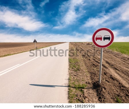 Straight asphalt road with a sign of prohibiting overtaking
