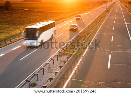 White bus in motion blur on highway at sunset