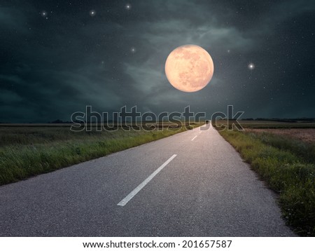 Driving on an empty asphalt road towards the full moon