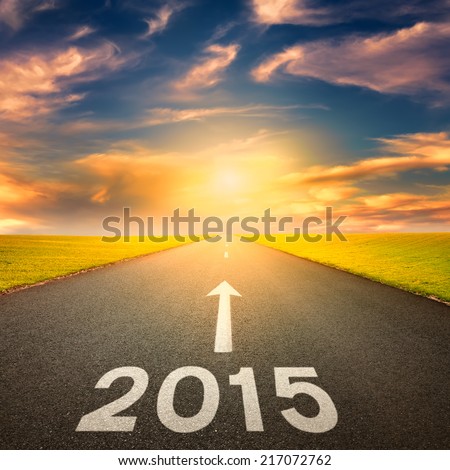 Driving on an empty road towards the setting sun to upcoming 2015