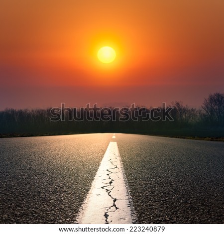 Driving on an empty road against the setting sun