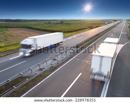 Two white trucks in motion blur on highway at sunny day near Belgrade - Serbia