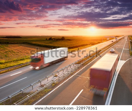 Two red trucks in motion blur on highway at sunset near Belgrade - Serbia
