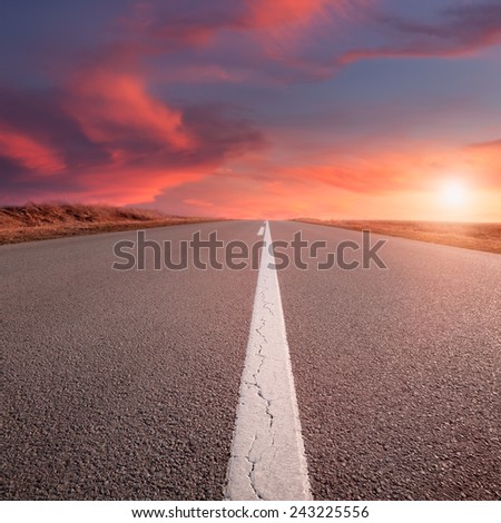 Driving on an empty road at sunset. Focus on the beginning of the asphalt road