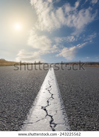 Driving on an empty road at sunny day. Focus on the beginning of the asphalt road