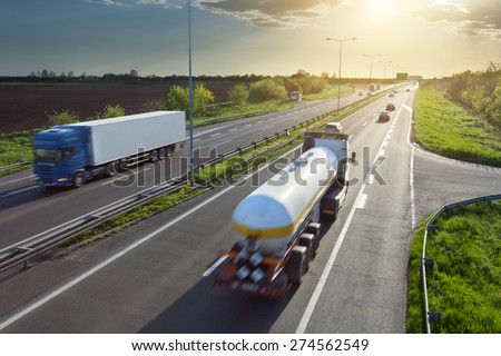 Two trucks in motion blur on the freeway towards the setting sun. Rush hour on the motorway near Belgrade - Serbia.