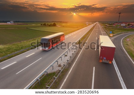 Truck and bus driving in motion blur on the freeway towards the setting sun. Rush hour on the highway near Belgrade - Serbia.