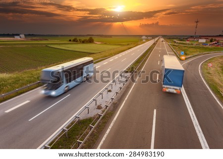 Truck and bus driving in motion blur on the freeway towards the setting sun. Rush hour on the motorway near Belgrade - Serbia.