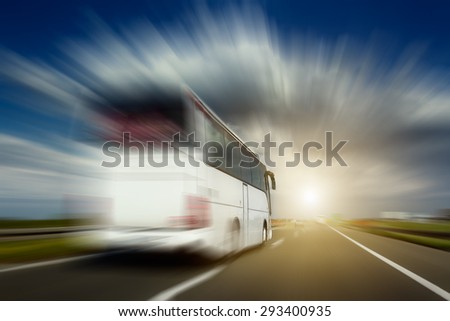 White bus in blurred motion at full speed performs overtaking on the highway. Photographed from the car when driving.