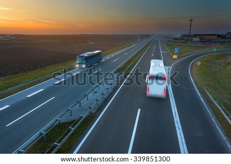Two buses driving in motion blur on the freeway at beautiful sunset. Rush hour on the motorway near Belgrade - Serbia.