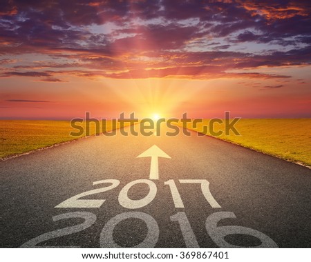 Driving on an empty road towards the setting sun to upcoming 2017 and leaving behind old 2016. Concept for success and passing time.