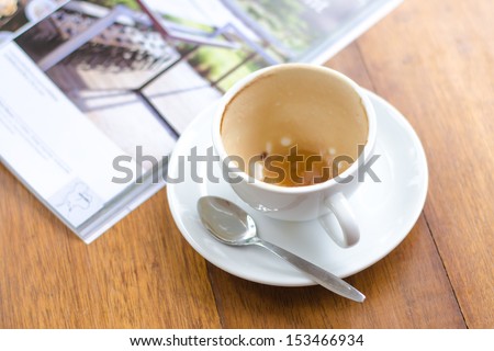 an empty cup of coffee and magazine on the wooden table