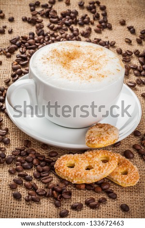 Cappuccino coffee and spilled coffee beans