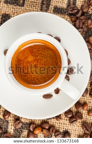 Espresso, cup of coffee, spilled coffee beans, top view