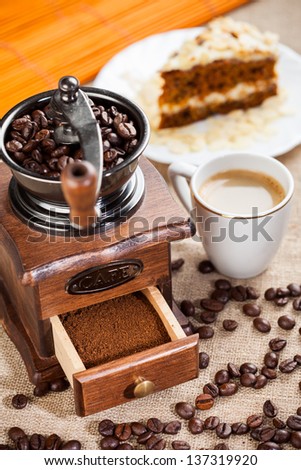 Coffee grinder, cup of coffee and cake