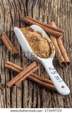 Ground cinnamon spice ,and five pieces of cinnamon barks, old wood background
