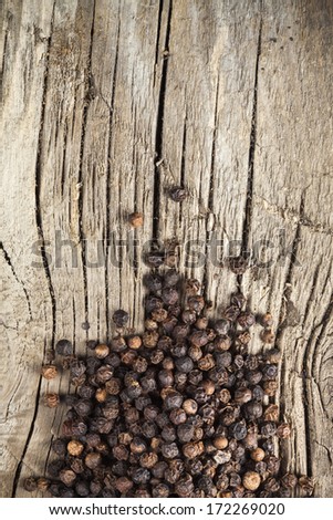 Black pepper spice spilled on old wood plank