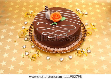 Chocolate cake with white chocolate ornaments and orange marzipan rose
