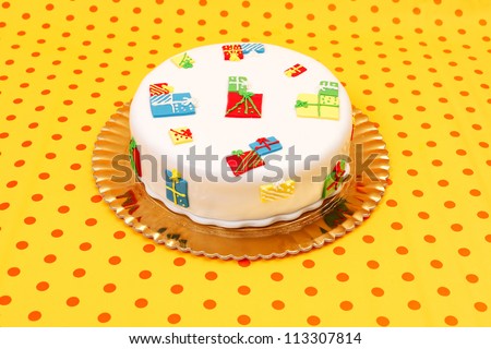 White birthday cake with marzipan ornaments on dotted orange background