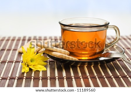 Tea and dry biscuit on bamboo tablecloth, yellow flower decoration