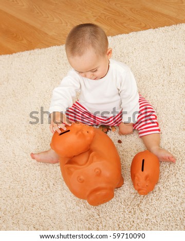 Little boy playing with several clay piggy banks on the floor