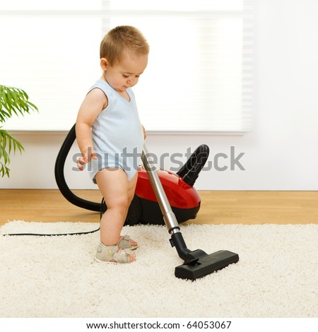 Baby boy cleaning the carpet with vacuum cleaner