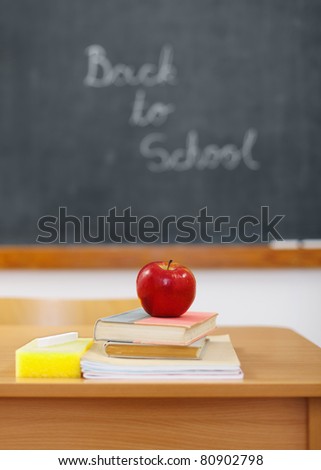 Back to school on chalkboard and red apple on books in front (focus on apple)