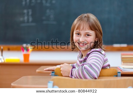Elementary school girl in classroom, turning back and smiling