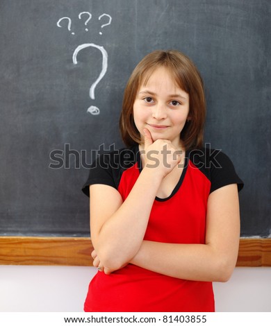 Elementary school girl thinking at chalkboard, question mark behind her