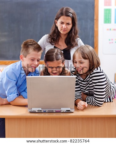 Kids surfing on the internet, watching unsafe content. Teacher stands behind and worries about