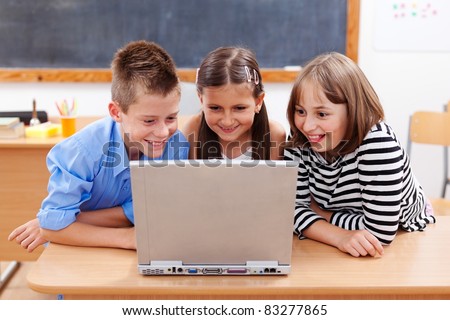 Happy children looking at laptop computer, surfing interesting content on the internet