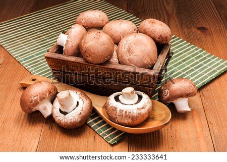 Fresh brown mushrooms in wooden box on board