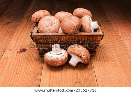 Fresh brown champignons in wooden box on board