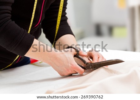 Dressmaker cutting fabric with big old steel scissors