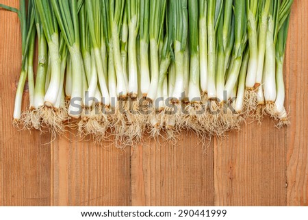 Lots of spring onions on wooden board