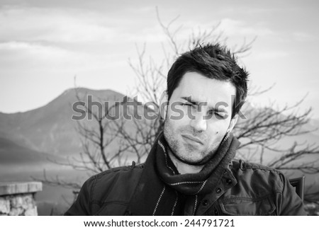 young handsome man with curious face, black and white, nature background