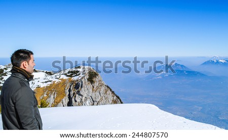 winter landscape, man looking at view of high mountains with beautiful blue sky background