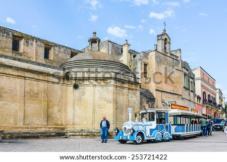 MATERA, ITALY- MAY 3, 2013: Tourists getting on tourist train for sightseeing in front of church Domenico on May 3, 2013. One of tourist attractions in Matera; world heritage site in Basilicata, Italy