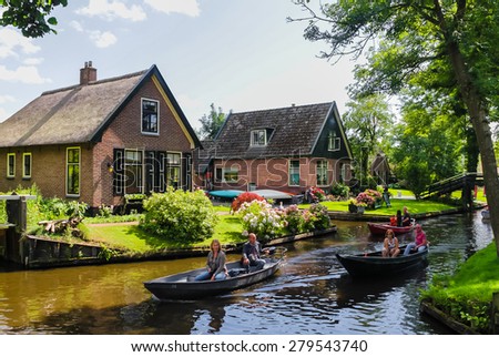 GIETHOORN, NETHERLANDS - AUGUST 13, 2013: Unknown visitors in the sightseeing boating trip in a canal in Giethoorn. The beautiful houses and gardening city is know as \