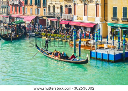 VENICE, ITALY- FEBRUARY 7: Gondolier and tourists on gondola in Venetian lagoon passing by hotels and restaurants by canal, Venice, Italy on February 7, 2015. Venice\'s  been known as \