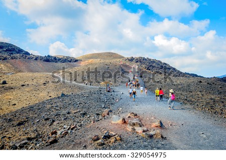 NEA KAMENI, SANTORINI, GREECE- OCTOBER 5, 2015: Hiking group of tourists on volcanic island Nea Kameni. The uninhabited volcanic island in Aegean sea, Mediterranean, Greece.