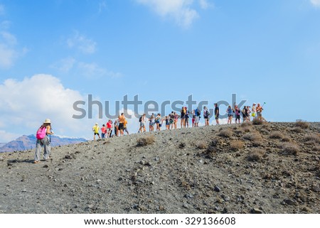 NEA KAMENI, SANTORINI, GREECE- OCTOBER 5, 2015: Hiking group of tourists on volcanic island Nea Kameni. The uninhabited volcanic island in Aegean sea, Mediterranean, Greece.