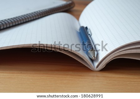 A metal pen between the pages of a exercise book. Macro image with shallow depth of focus.